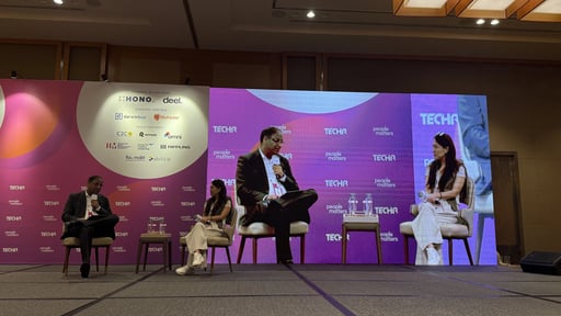 Close-up of a TechHR panel discussion with speakers holding microphones and engaging in conversation on stage.
